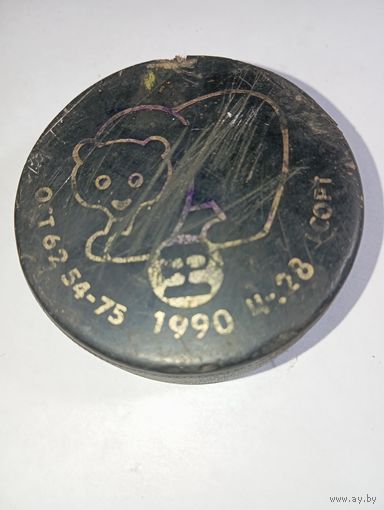 Коллекционная хоккейная шайба времен СССР, выпущенная в 1990 году. На ней изображен медвежонок (возможно, вариация олимпийского Мишки или символ турнира тех лет).