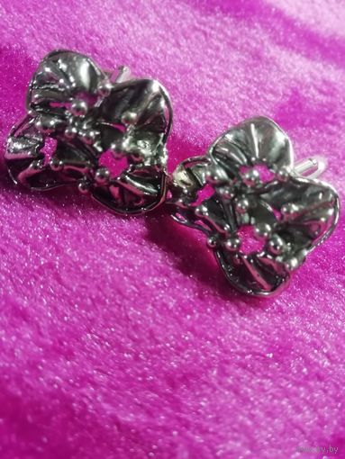 Запонки в форме цветов или абстрактных узлов из серебристого металла.
